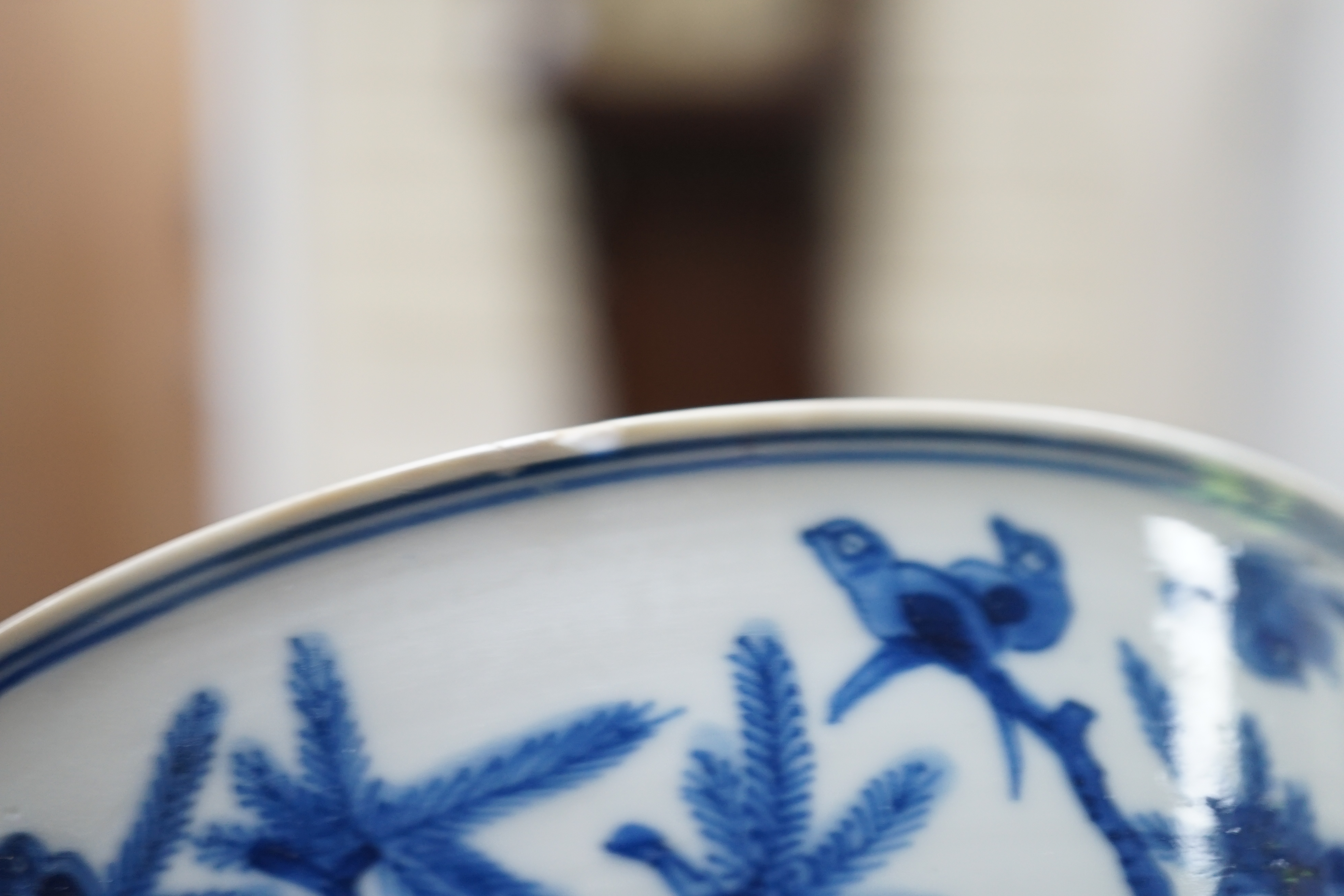 A near pair of Chinese blue and white ‘birds’ bowls, Kangxi period, one bowl restored